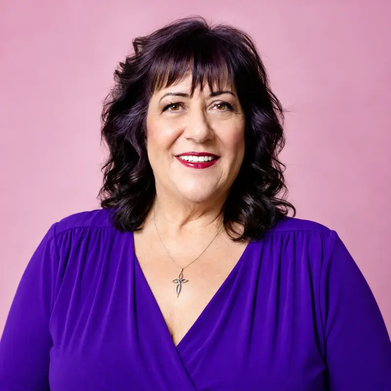Studio portrait of a smiling woman with dark hair wearing a royal purple dress against a pink background.